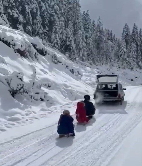 Çorum'un İskilip ilçesinde bir esnaf, aracının arkasına bağladığı kızaklarla çocuklarını