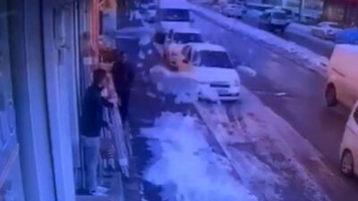 Gaziantep’te, bir iş yerinin önünde bekleyen bir çalışan, çatıda biriken