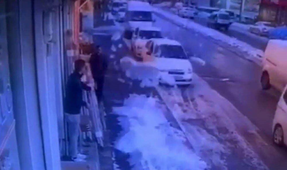 Gaziantep’te, bir iş yerinin önünde bekleyen bir çalışan, çatıda biriken