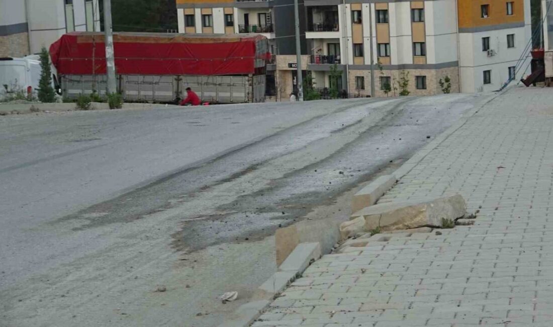 Hatay’da yerel bir mahallede, asfalt yol üzerinde kepçe ile ilerleyen
